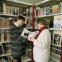 Bibliotheekmedewerker toont boek aan bezoeker.
